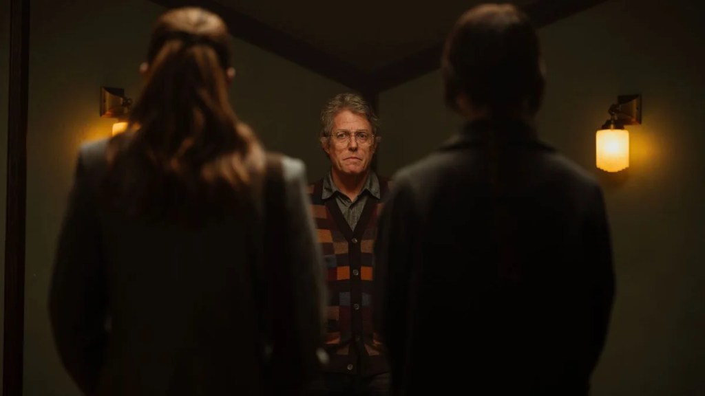 Hugh Grant stands between Chloe East and Sophie Thatcher in "Heretic."