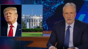 Jon Stewart sits near a Trump White House graphic on "The Daily Show."