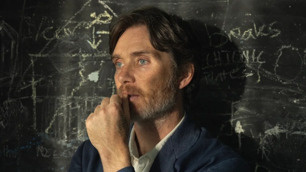 Cillian Murphy stands in front of a chalkboard
